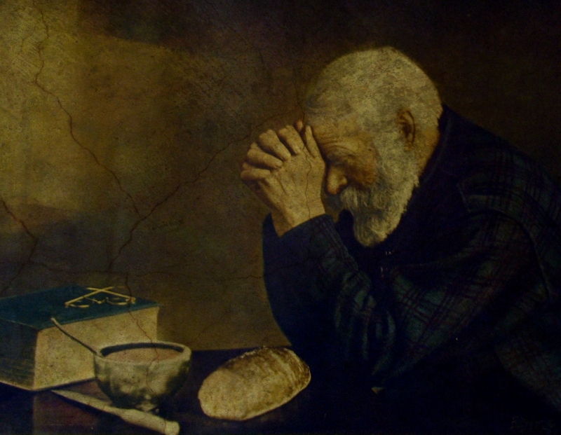 Man praying over loaf of bread, Bible on table