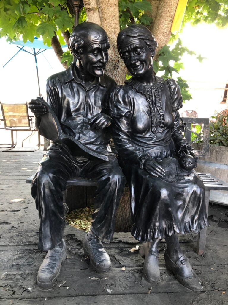 Statue of old contented couple (and their cat) sitting on beach and reading